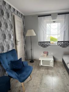 a living room with a blue chair and a couch at Dom nad jeziorem in Lubkowo