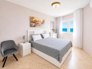 a white bedroom with a bed and a chair at Algaida, beach apartment in Mijas Costa
