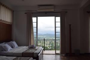 a bedroom with a bed and a large window at Sentinels Hotel Kandy in Kandy