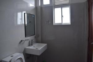 a white bathroom with a sink and a mirror at Sentinels Hotel Kandy in Kandy +30 photos