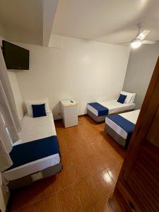 a room with two beds and a flat screen tv at Hotel Buriti da Serra in Itaipava