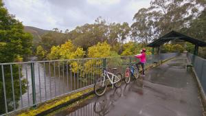a woman standing on a bridge with two bikes at Chalets Lumineux in Bright