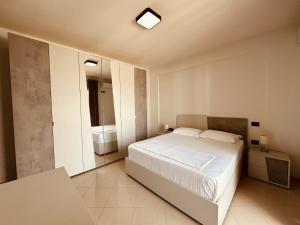 a bedroom with a white bed and a bathroom at Thoma's K Studios in Vlorë