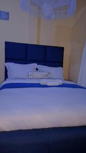 a large bed with a blue headboard and white pillows at BREE'S EXECUTIVE STAYs in Kakamega