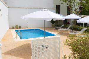 a swimming pool with an umbrella and two umbrellas at Hotel Casa de la Torrecilla in Campo de Criptana