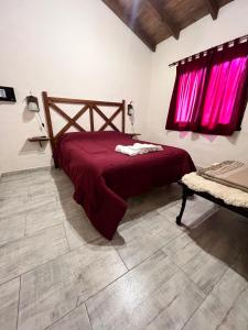 a bedroom with a red bed with pink curtains at Cabañas El Campo in Sierra de la Ventana