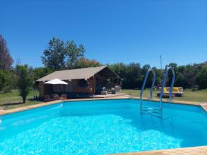 a swimming pool with a tent in the background at casa la luna glamping in Alhaurín el Grande