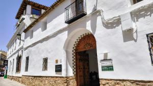 a white building with a wooden door in a street at Hotel Casa de la Torrecilla in Campo de Criptana