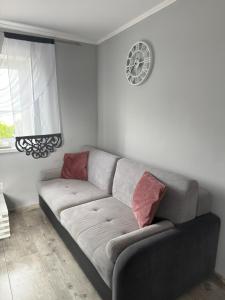 a couch in a living room with a clock on the wall at Dom nad jeziorem in Lubkowo