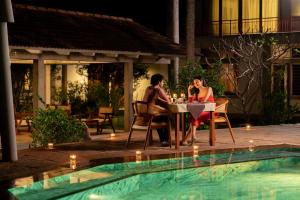 a man and woman sitting at a table near a pool at Sanctuary Amaidiyana - A CGH Earth Experience in Pondicherry +131 photos
