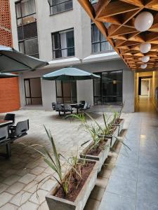 a patio with tables and chairs and an umbrella at GCurtway Homes Tsavo Superior Studios in Nairobi
