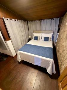 a bedroom with a large bed with blue and white pillows at Hotel Buriti da Serra in Itaipava