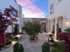 a courtyard with tables and trees in a building at Palazzo Muro Leccese Relais de Charme & Wellness in Muro Leccese