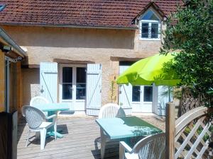 a patio with a table and chairs and an umbrella at Villa EsquirHall, chambres d'hôtes in Journiac