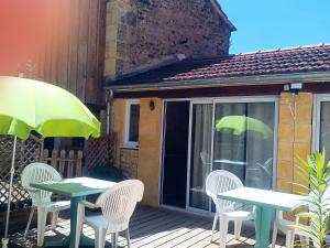 a patio with two tables and chairs and an umbrella at Villa EsquirHall, chambres d'hôtes in Journiac