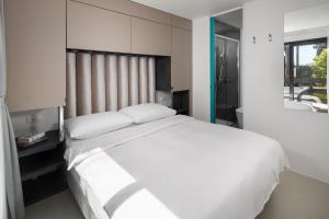 a bedroom with a large white bed and a bathroom at Boutique Camping Materada Beach in Poreč +50 photos