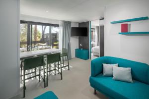a living room with a blue couch and a kitchen at Boutique Camping Materada Beach in Poreč