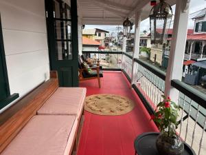 a balcony with a red floor and a bench and a rug at Coffee Mama Stay in Paramaribo