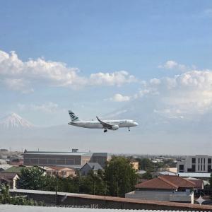 an airplane is flying in the sky over a city at Elkasa guest house in Zvartnots International Airport