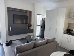 a living room with a couch and a tv on a wall at Muzo Guest Nest in Cape Town +4 photos