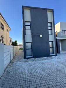 a building with a blue door on a brick driveway at Muzo Guest Nest in Cape Town