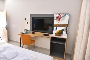 a room with a television and a desk with a chair at Vels Grand Hotel in Kanchipuram