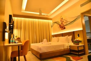 a hotel room with a bed and a desk and a television at Vels Grand Hotel in Kanchipuram