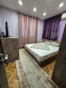 a bedroom with a large bed and purple curtains at Апартамент riverside in Yambol