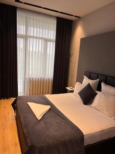 a bedroom with a large bed with a large window at Hotel Elion in Yerevan