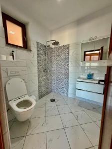 a white bathroom with a toilet and a sink at Hotel Te Liqeni in Peje