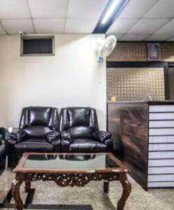 a living room with black leather chairs and a coffee table at Hotel Tirumala in Secunderabad