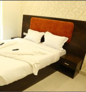 a bedroom with a large white bed with an orange headboard at Hotel Tirumala in Secunderabad