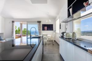 a kitchen with white cabinets and a view of the ocean at Villa La Gioia in Terra Mala +86 photos
