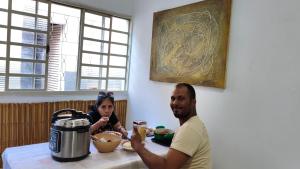 a man and a woman sitting at a table eating food at Nomah Hostel in Sao Jose do Rio Preto +4 photos