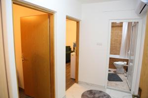 a bathroom with a toilet and a door with a mirror at City Apartman 103 in Bosanski Brod