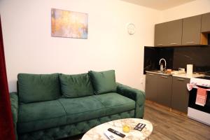 a living room with a green couch and a table at City Apartman 103 in Bosanski Brod