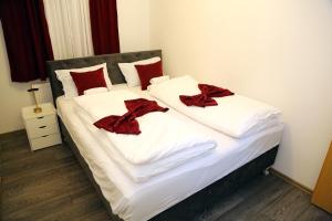 a bed with white sheets and red pillows at City Apartman 103 in Bosanski Brod +1 photo