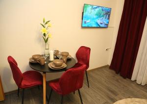 a dining room with a table and red chairs at City Apartman 103 in Bosanski Brod