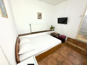 a small bedroom with a bed and a television at Pensiunea Pitaru in Calafat +4 photos