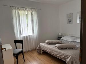 a bedroom with a bed and a chair and a window at Kuća za odmor Belvedere in Siverić