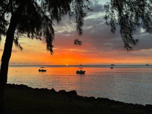 two boats on the water at sunset at Cosy Studio 71 in Petite Case Noyale