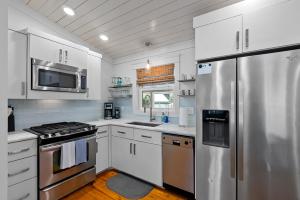a kitchen with white cabinets and a stainless steel refrigerator at Downtown Fairhope Cottage in Fairhope
