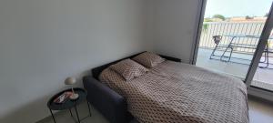 a bedroom with a bed and a balcony with a table at L'Appar-TMN in Challans