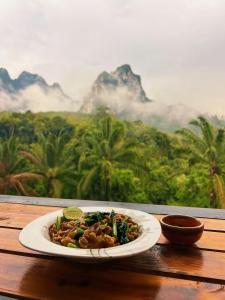 a plate of food on a table with a view of mountains at Khaosok Malinglamping in Ban Thung Lang Tham