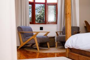 a bedroom with two chairs and a table and a bed at The Valley Escape - Executive Suite in Gqeberha +27 photos