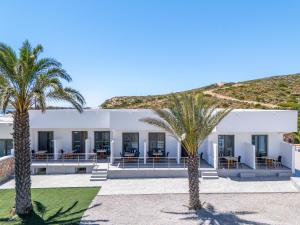 a white building with palm trees in front of it at Prasonisi Lighthouse Asimenis in Prasonisi