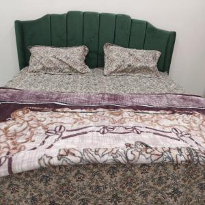 a bed with a green headboard and a blanket at Atlas blue hotel in Bathinda