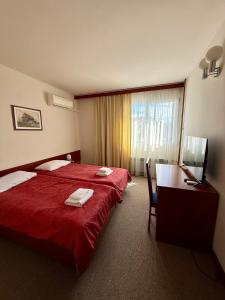 a hotel room with a red bed and a desk at Hotel Kutina in Kutina