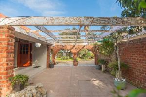 a brick building with a wooden pergola at The Valley Escape - Executive Suite in Gqeberha