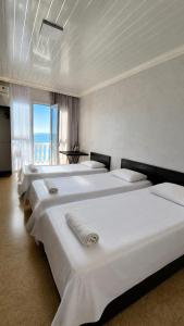 a row of white beds in a room with a window at У Царицы in Kobuleti +13 photos